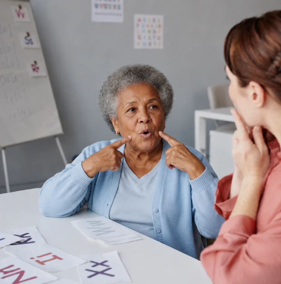Speech therapist coaching an older woman during a communication exercise