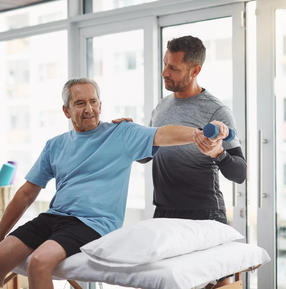 Physical therapist helping an older man with arm mobility exercise.