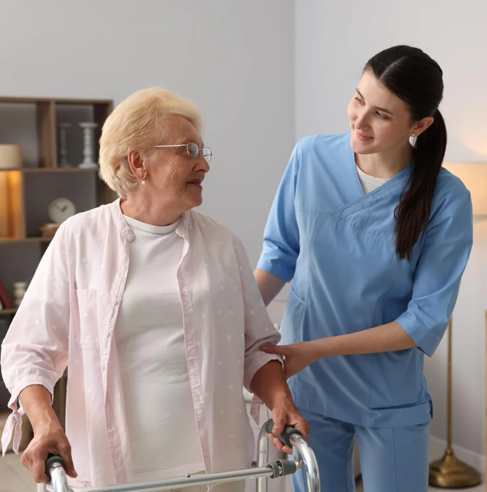 Caregiver assisting an older woman using a walker at home.