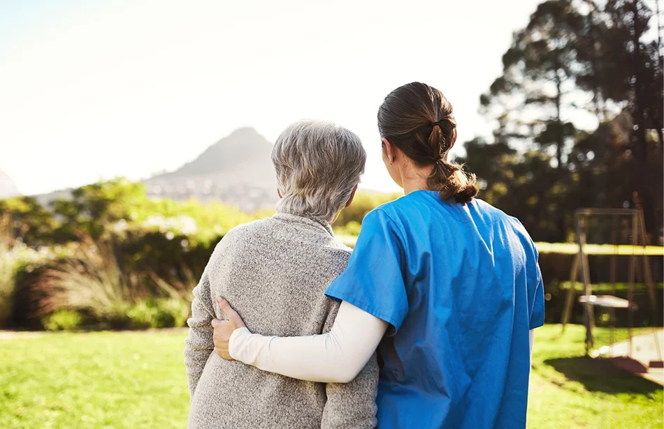 Caregiver walking outdoors with a senior woman