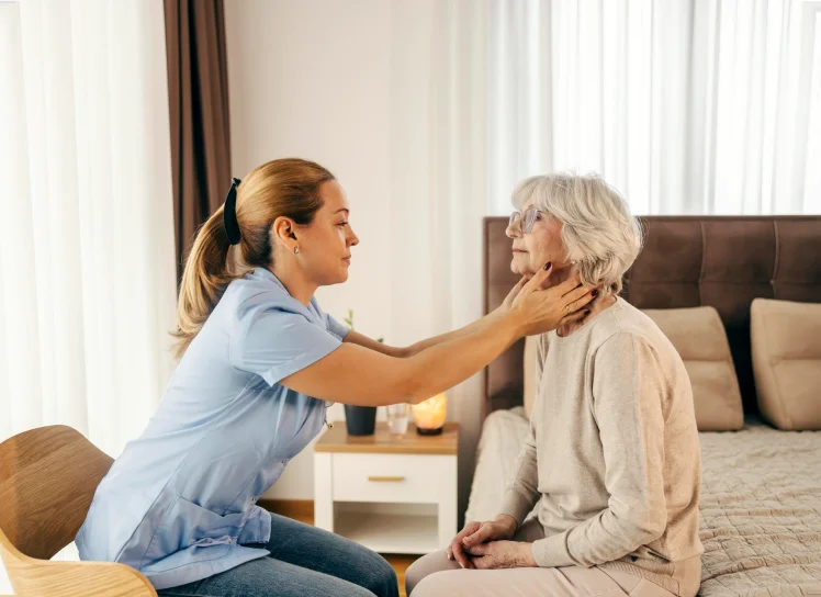 Therapist checking an older woman's swallowing or jaw movement