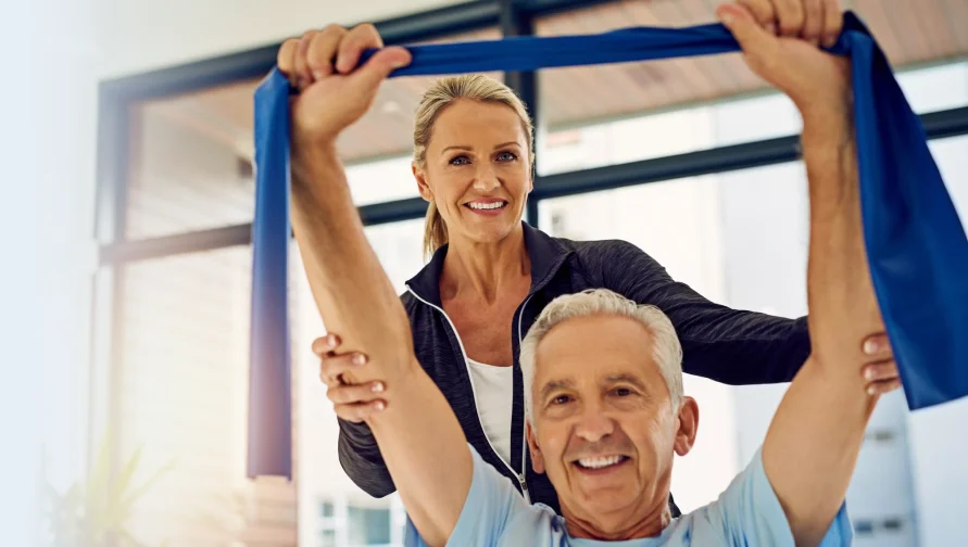 Older patient stretching with a resistance band during therapy.