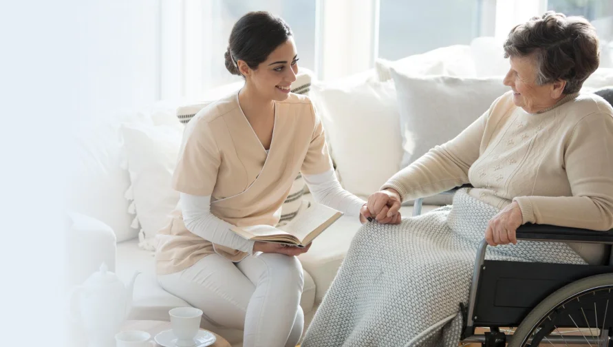 Social worker counseling an older woman in a wheelchair.