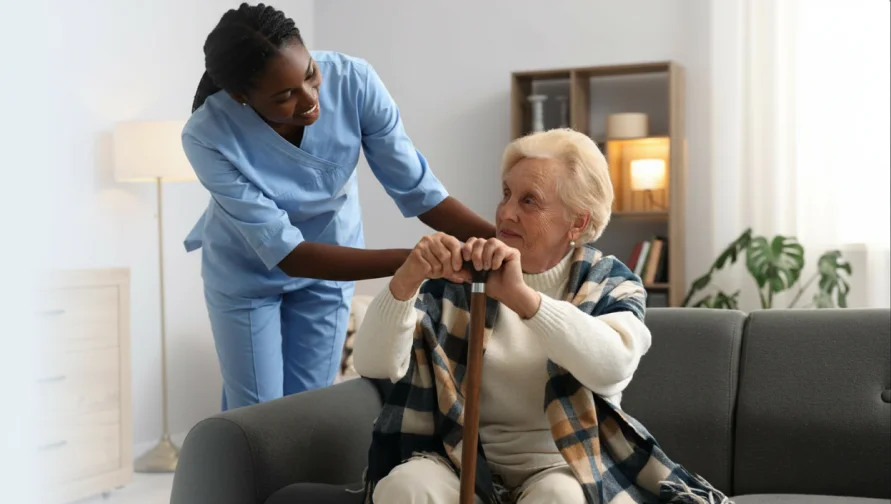 Aide helping an older woman dress at home.