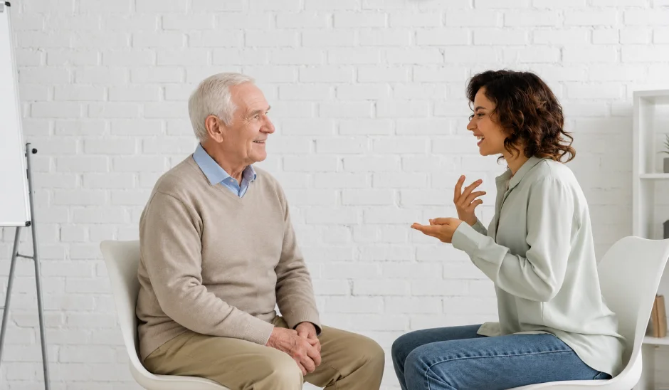 Speech therapist talking with an older man during a home session.