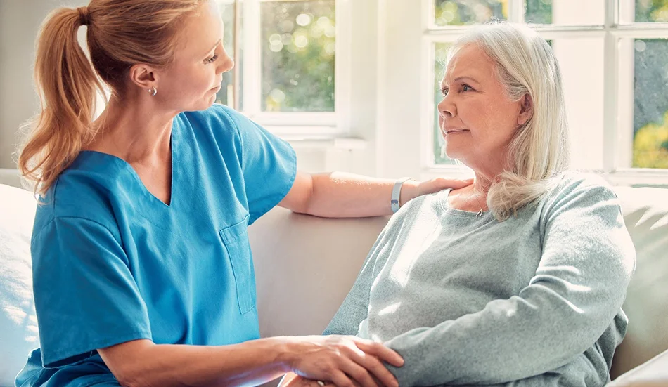 Caregiver providing emotional support to a senior woman at home