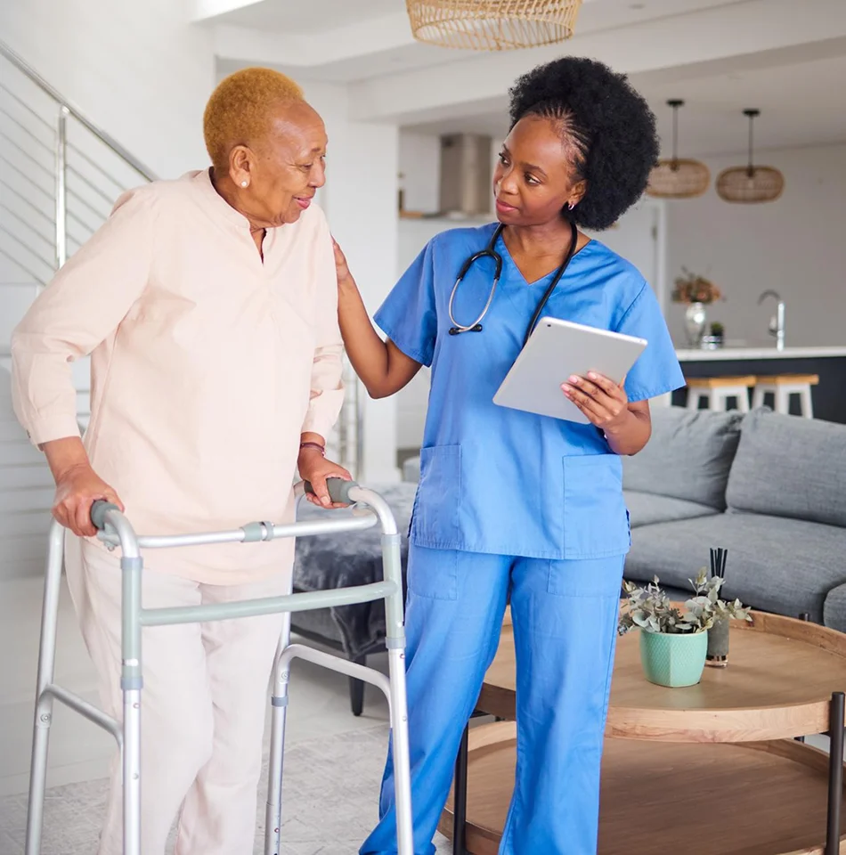 Home healthcare caregiver helping a senior woman walk safely with a walker