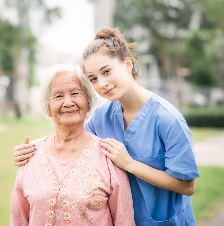 Caregiver standing with a smiling senior woman outdoors