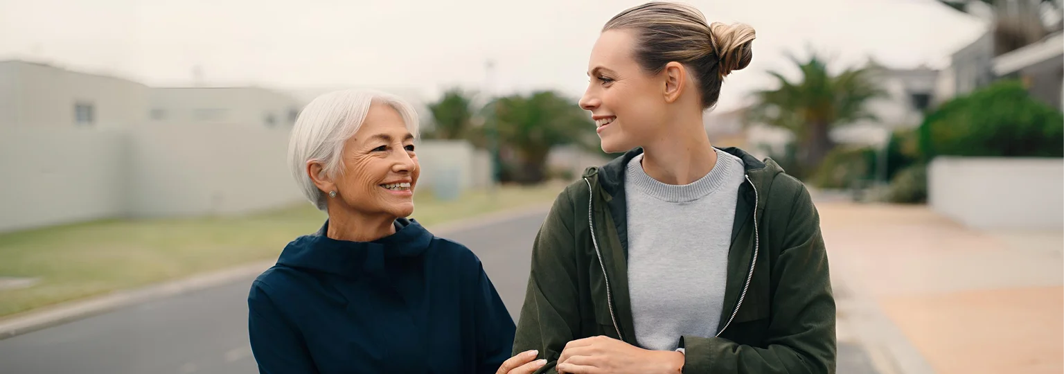 Caregiver walking outdoors with a senior woman