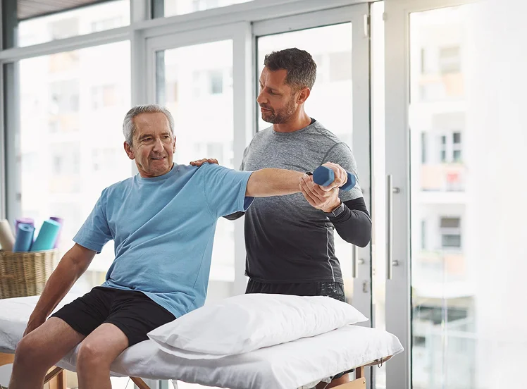 Physical therapist assisting a senior man with arm rehabilitation exercises