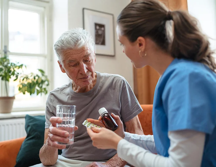 Caregiver helping a senior man organize his daily medications