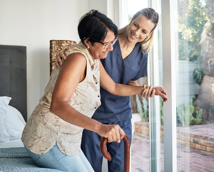 Caregiver assisting a senior woman with mobility using a cane